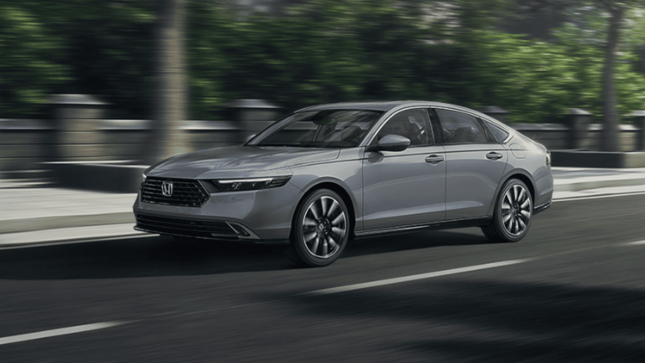 2025 Honda Accord sedan in silver driving on city street, side view with blurred urban background