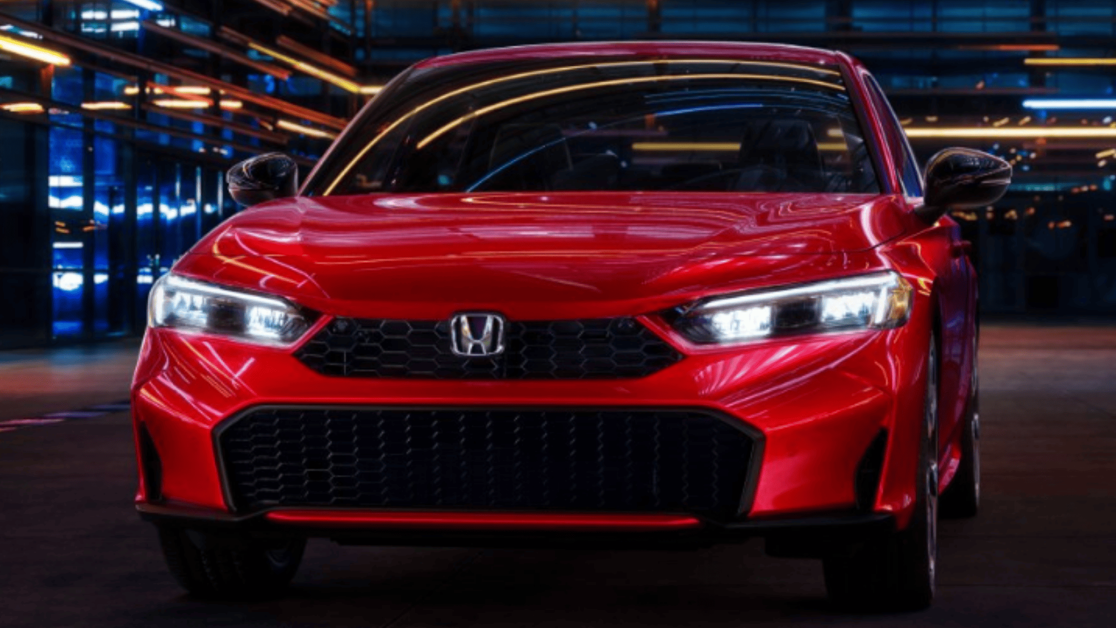 2026 Honda Civic Sedan in red front view parked under city lights with LED headlights illuminated