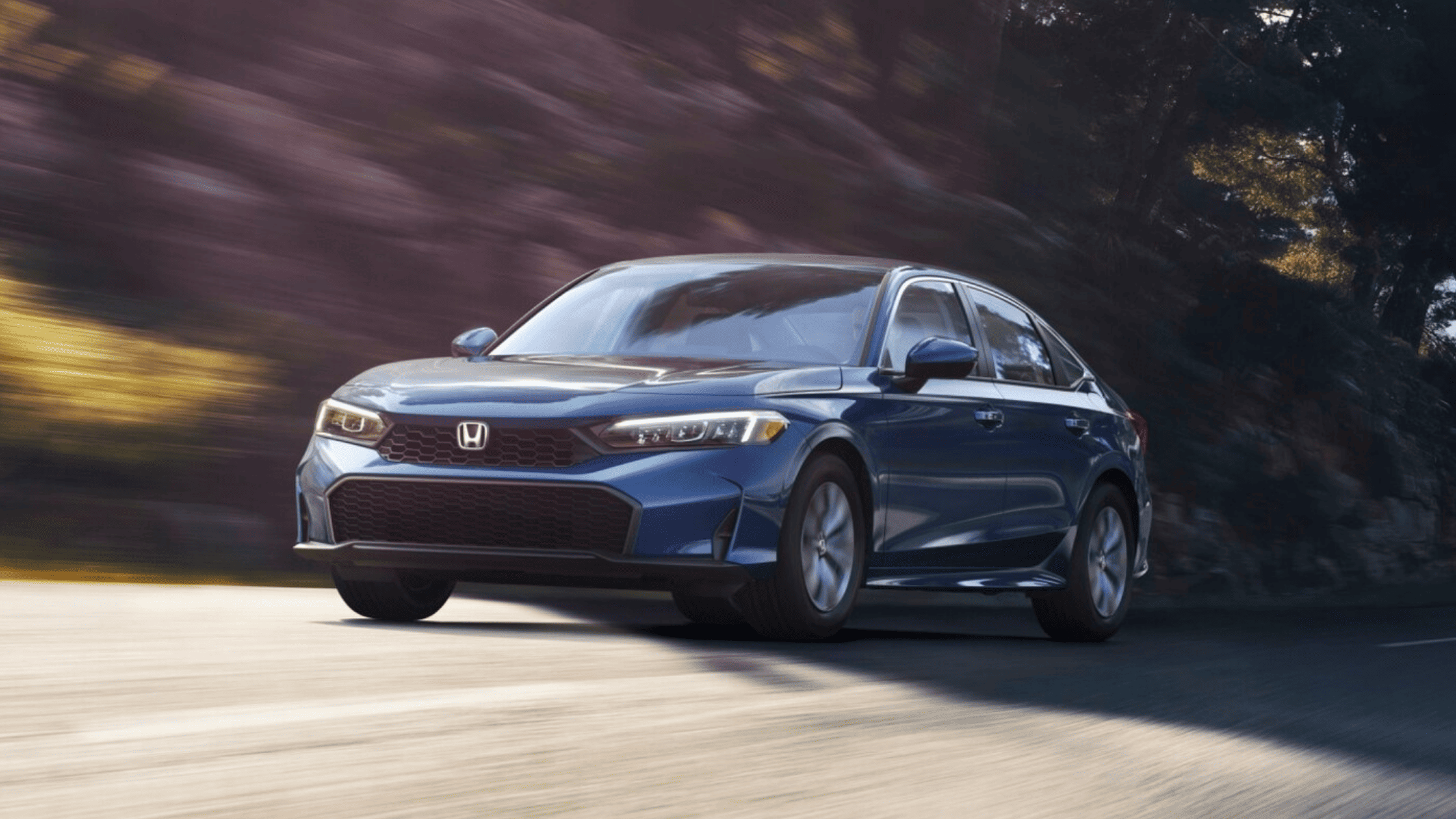 Blue 2025 Honda Civic sedan driving on a scenic road with motion blur effect.