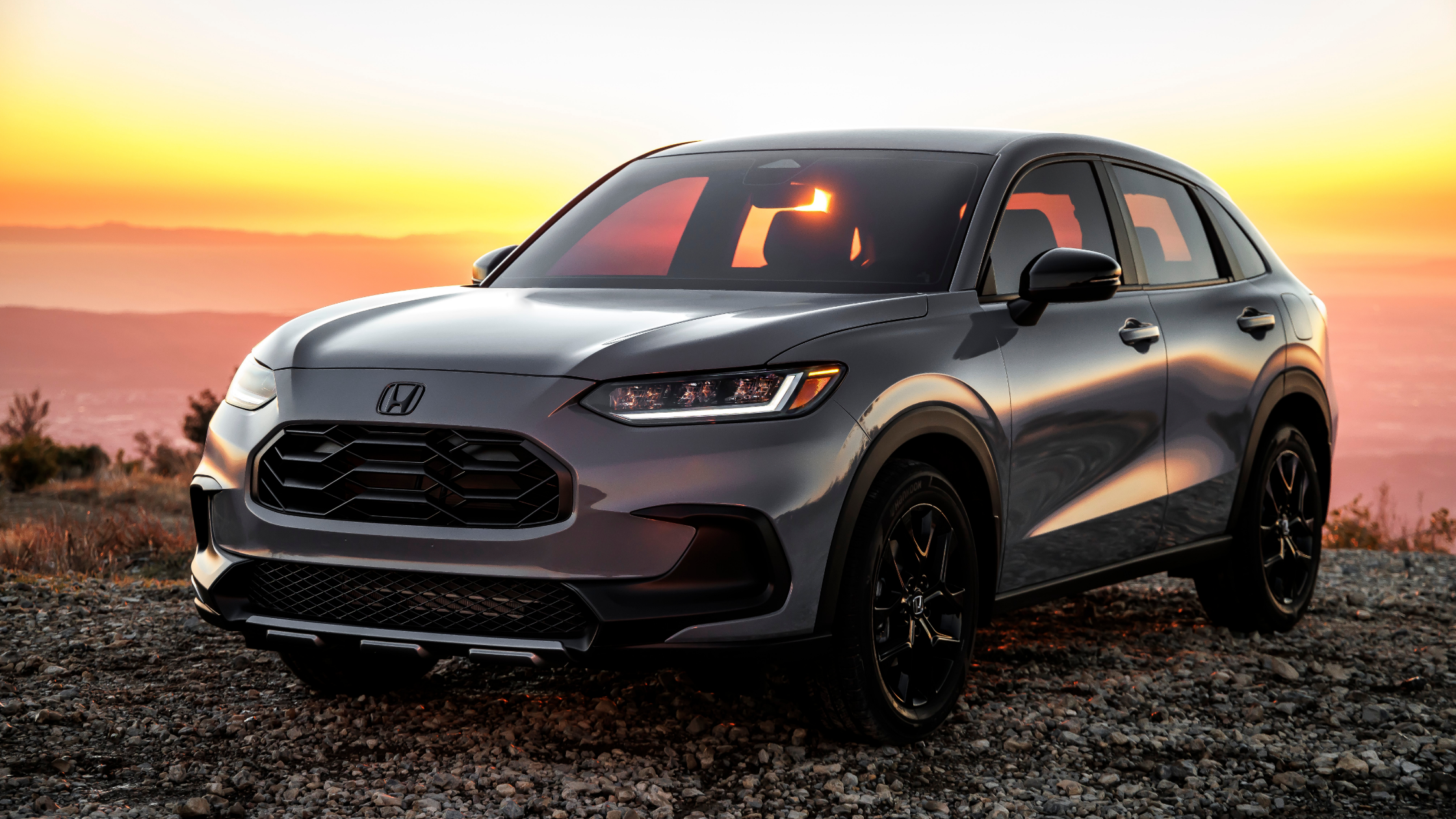 Gray Honda HR-V parked on gravel at sunset with scenic horizon views.