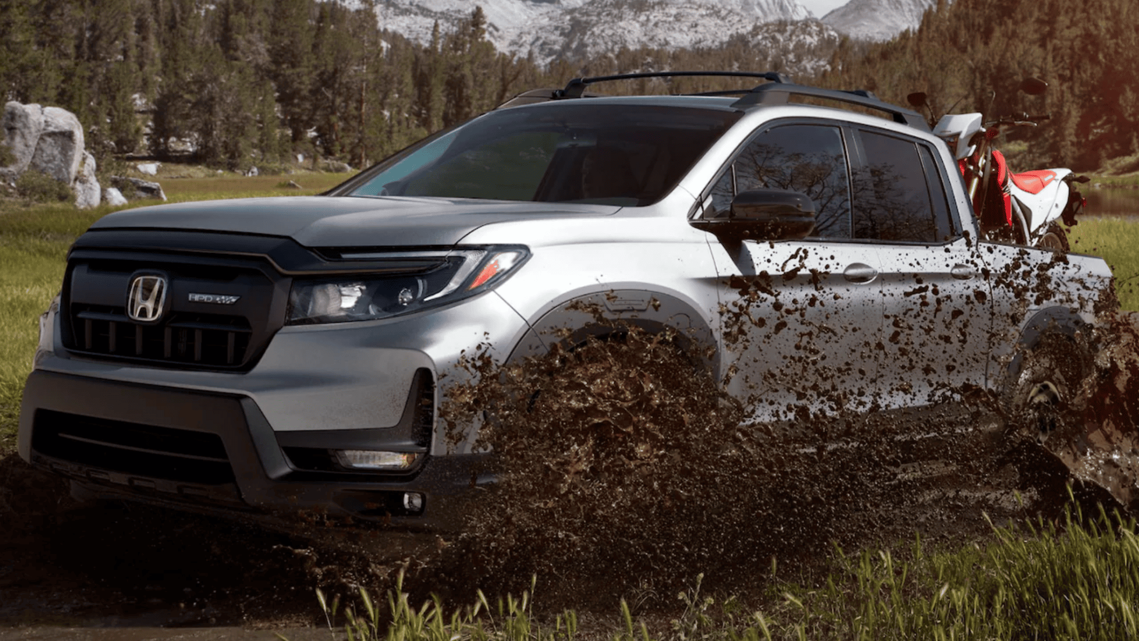 Close-up of the Honda Ridgeline's headlight, grille, and sleek white exterior.